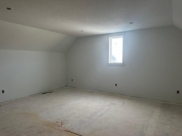 additional living space featuring a textured ceiling and lofted ceiling