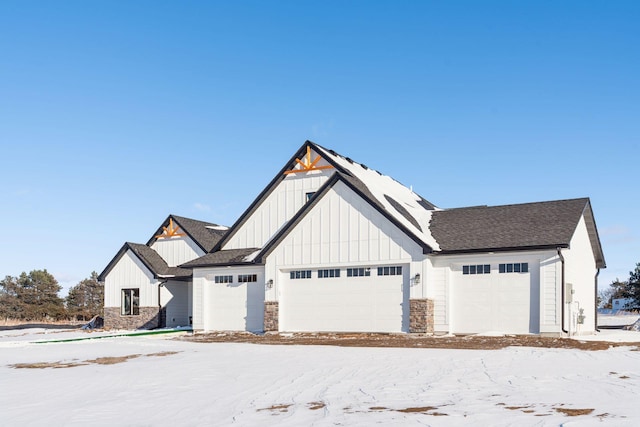 modern inspired farmhouse featuring roof with shingles, board and batten siding, and stone siding