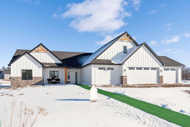 modern farmhouse featuring a garage, stone siding, board and batten siding, and roof with shingles