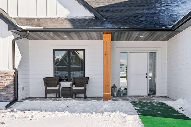 doorway to property featuring board and batten siding, covered porch, and roof with shingles