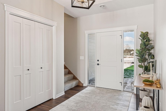 entrance foyer with dark wood finished floors, baseboards, and stairs