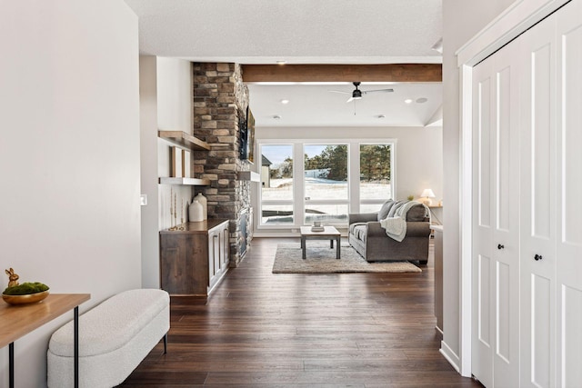 living room with dark wood-style floors, ceiling fan, a textured ceiling, and beamed ceiling