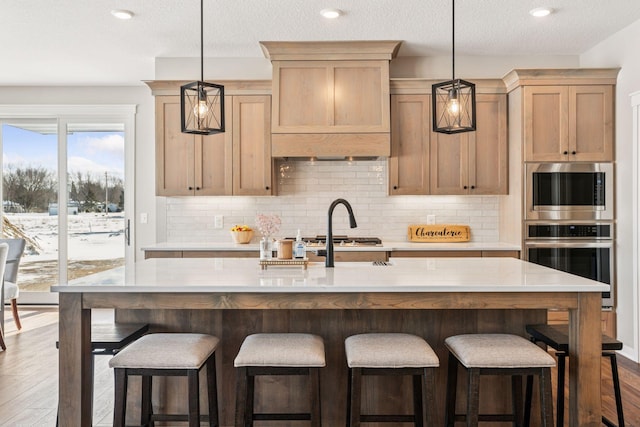 kitchen featuring decorative backsplash, appliances with stainless steel finishes, wood finished floors, light countertops, and pendant lighting