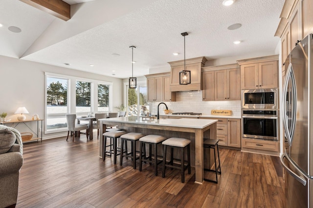 kitchen with a breakfast bar, light countertops, appliances with stainless steel finishes, backsplash, and dark wood-style floors