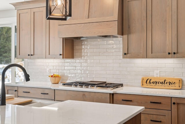 kitchen with plenty of natural light, stainless steel gas cooktop, decorative backsplash, and a sink