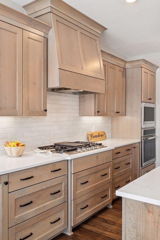 kitchen with appliances with stainless steel finishes, tasteful backsplash, custom exhaust hood, and light brown cabinetry