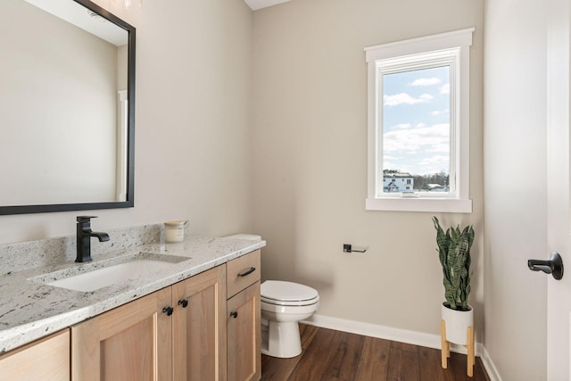 bathroom featuring toilet, baseboards, wood finished floors, and vanity