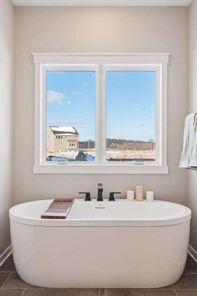 full bathroom featuring a soaking tub and baseboards