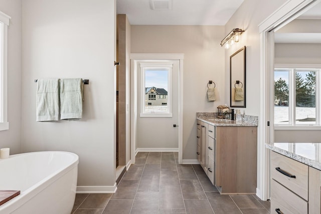 full bathroom with a freestanding bath, a wealth of natural light, vanity, and baseboards