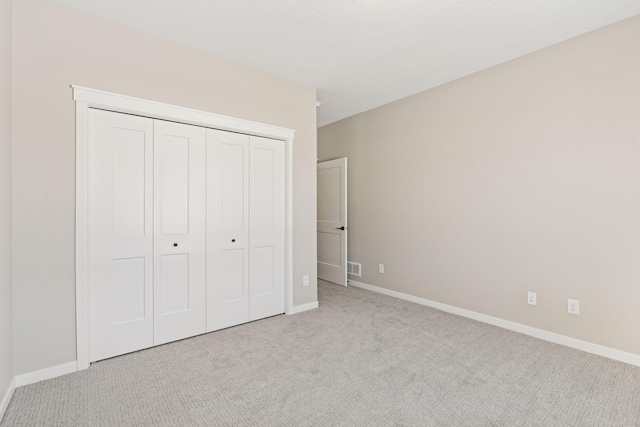 unfurnished bedroom with carpet floors, a closet, visible vents, and baseboards