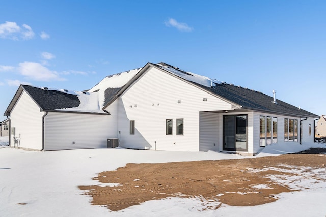 snow covered back of property featuring central AC