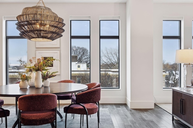 dining room with wood-type flooring, a healthy amount of sunlight, and an inviting chandelier