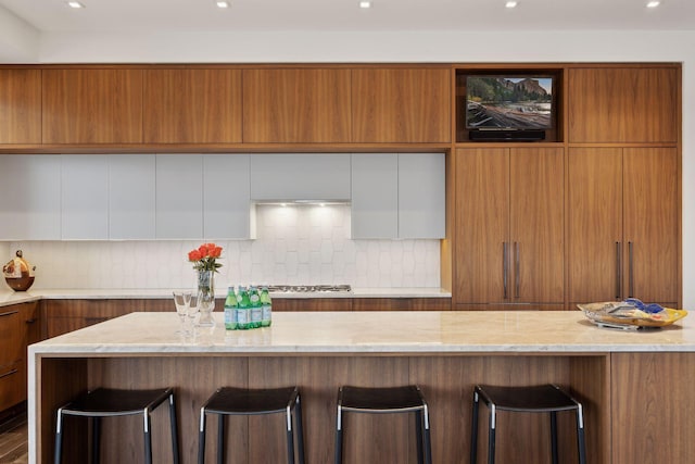 kitchen with white cabinetry, a kitchen breakfast bar, and decorative backsplash