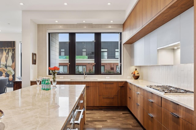 kitchen featuring backsplash, light stone counters, white cabinets, dark hardwood / wood-style flooring, and stainless steel gas stovetop