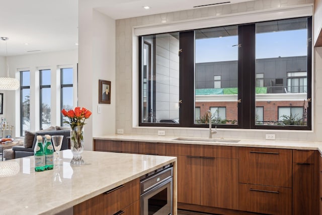 kitchen featuring decorative light fixtures, oven, and sink