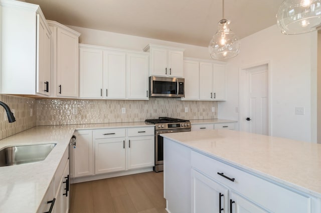 kitchen featuring hanging light fixtures, appliances with stainless steel finishes, sink, and white cabinets