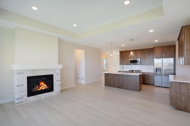 13104 Ghia Ct NE, Blaine, MN 55449 - kitchen with stainless steel appliances, a center island with sink, open floor plan, backsplash, and a fireplace