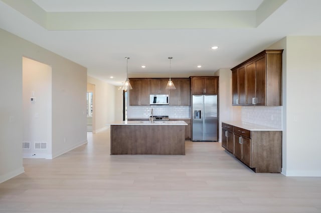 13104 Ghia Ct NE, Blaine, MN 55449 - kitchen with stainless steel fridge, white microwave, tasteful backsplash, an island with sink, and light countertops