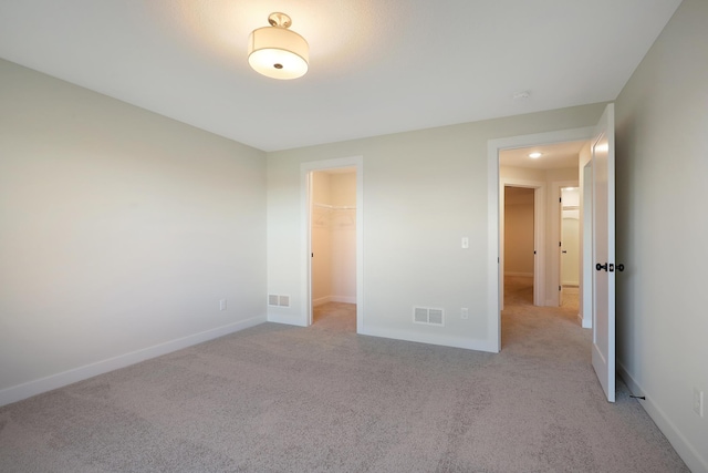 13104 Ghia Ct NE, Blaine, MN 55449 - unfurnished bedroom featuring light carpet, baseboards, a walk in closet, and a closet