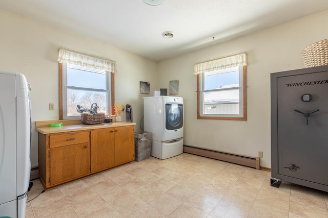 laundry area with a baseboard heating unit, plenty of natural light, and washer / clothes dryer