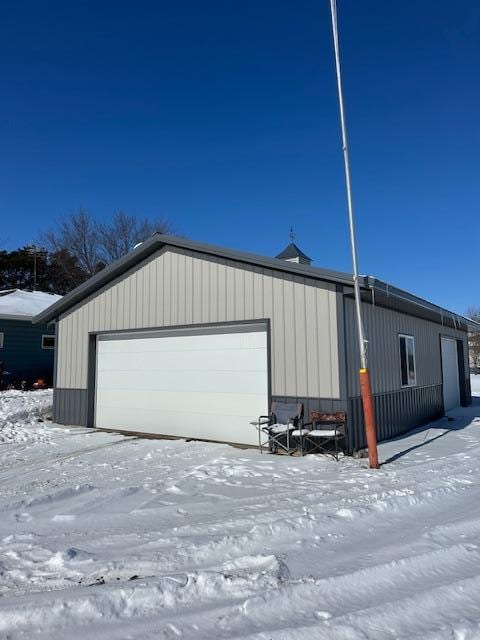 snow covered garage featuring a detached garage