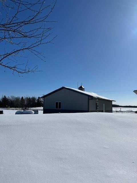 snow covered property featuring an outdoor structure and a pole building