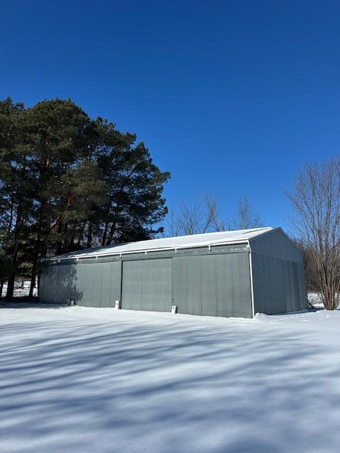 snow covered structure featuring an outdoor structure and an outbuilding