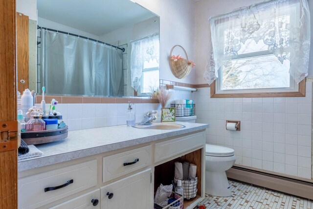 13959 55th St NE, Foley, MN 56329 - bathroom with a baseboard radiator, vanity, toilet, tile patterned floors, and tile walls