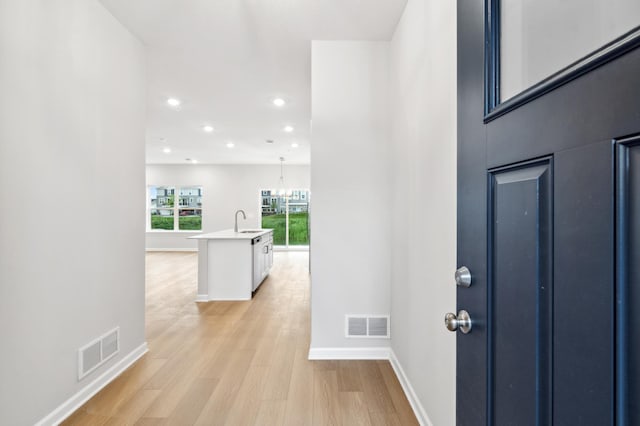 entrance foyer featuring an inviting chandelier, sink, and light hardwood / wood-style flooring