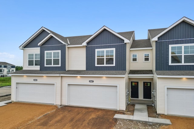 view of property with an attached garage, driveway, roof with shingles, and board and batten siding