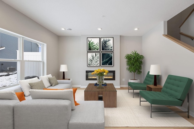 living room with recessed lighting, light wood-type flooring, baseboards, and a glass covered fireplace