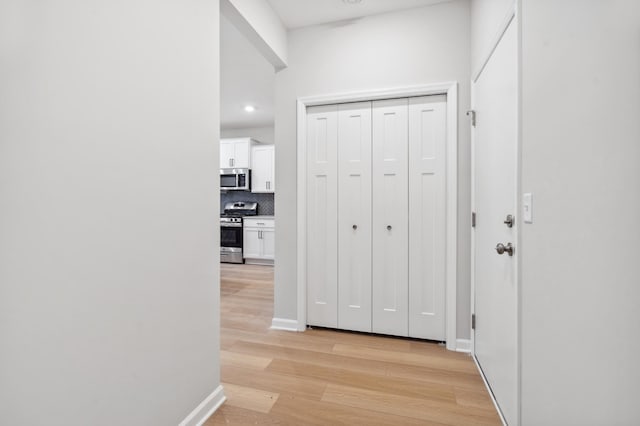 hall featuring recessed lighting, baseboards, and light wood finished floors