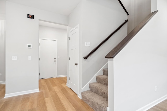 interior space with light wood-type flooring, baseboards, and stairs