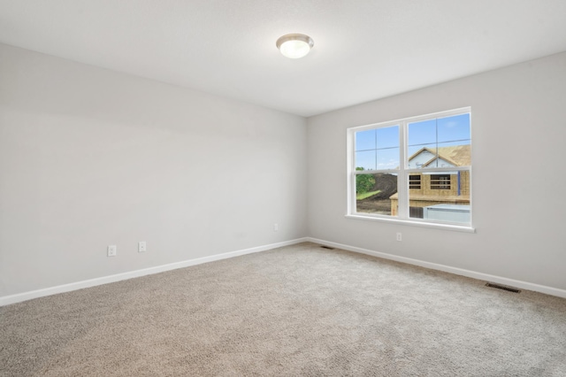 carpeted spare room featuring visible vents and baseboards