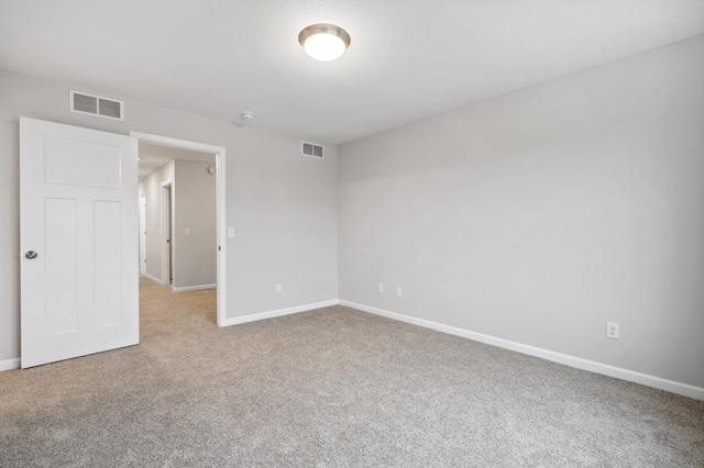 carpeted empty room with visible vents and baseboards