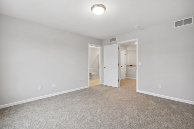 unfurnished bedroom with light colored carpet, visible vents, ensuite bathroom, and baseboards