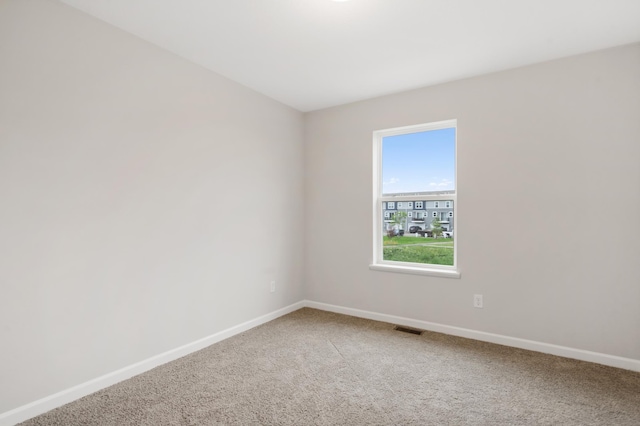 empty room featuring visible vents, baseboards, and light colored carpet