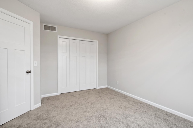 unfurnished bedroom with carpet, visible vents, a closet, and baseboards