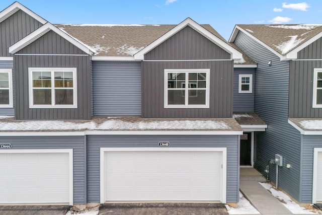 view of property with board and batten siding, a garage, and roof with shingles