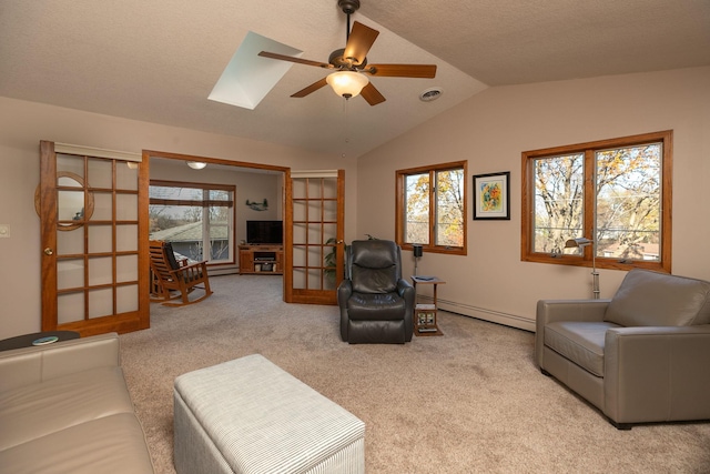 living room with vaulted ceiling with skylight, a baseboard heating unit, french doors, ceiling fan, and light colored carpet