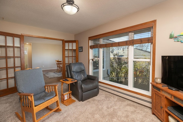 sitting room featuring light carpet, baseboard heating, and a textured ceiling