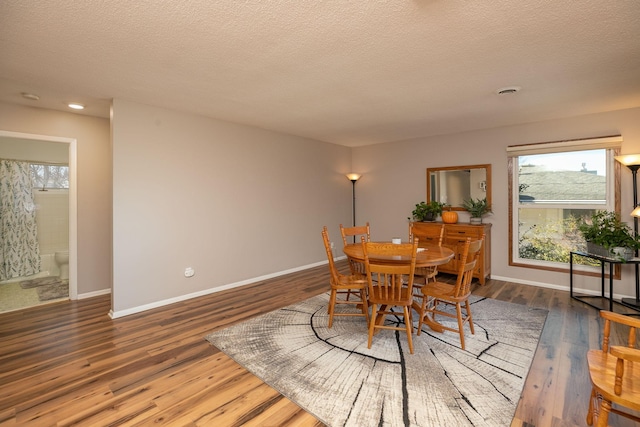 dining area with dark wood-type flooring and a textured ceiling