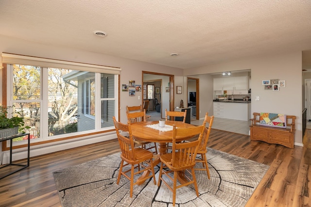 dining area with a textured ceiling, a baseboard heating unit, and dark hardwood / wood-style flooring