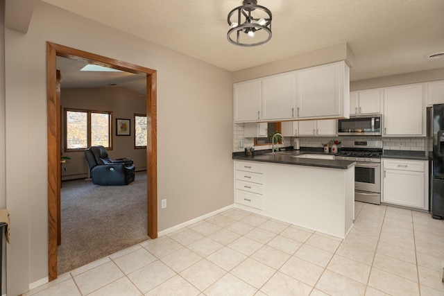 kitchen featuring vaulted ceiling, light carpet, white cabinets, backsplash, and stainless steel appliances