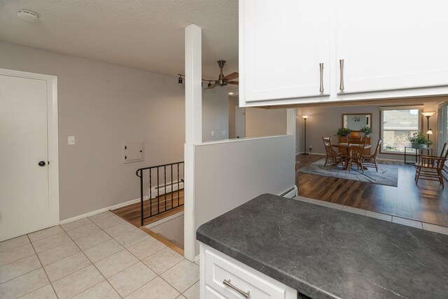 kitchen with a baseboard radiator, white cabinetry, light tile patterned floors, and a textured ceiling