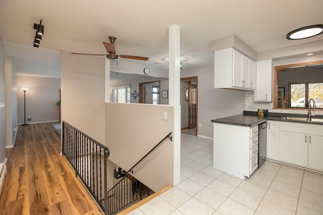 kitchen with tasteful backsplash, dishwasher, white cabinetry, sink, and ceiling fan