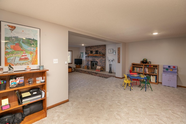 game room with a textured ceiling, light colored carpet, and a fireplace