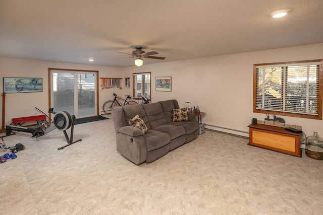 living room with ceiling fan, a healthy amount of sunlight, baseboard heating, and light carpet