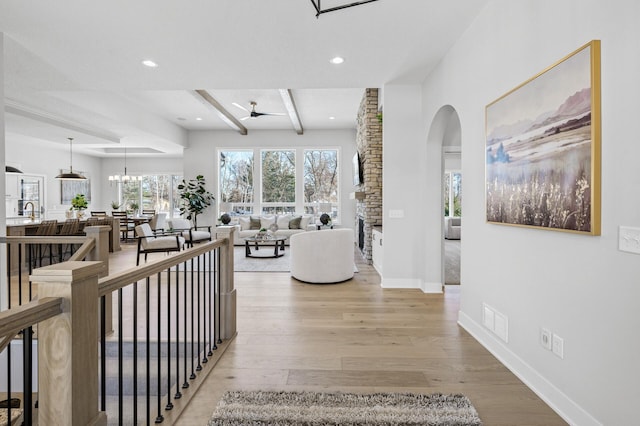 interior space featuring light wood-type flooring, an inviting chandelier, beam ceiling, and sink