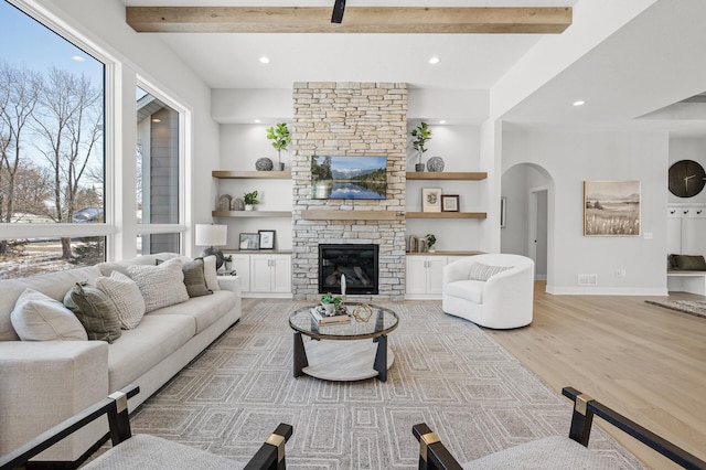 living room with beam ceiling, a fireplace, a wealth of natural light, and light hardwood / wood-style floors